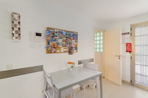 A room with a glass table, white chairs, a bulletin board with various papers, a white door, and a window with blinds. - Vacation 'Pure Luxury and Comfort La Oliva' with Mountain View, Wi-Fi and Air Conditioning (La Playa de Tauro)