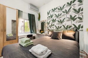 Un dormitorio con cama, escritorio, espejo y armario.
