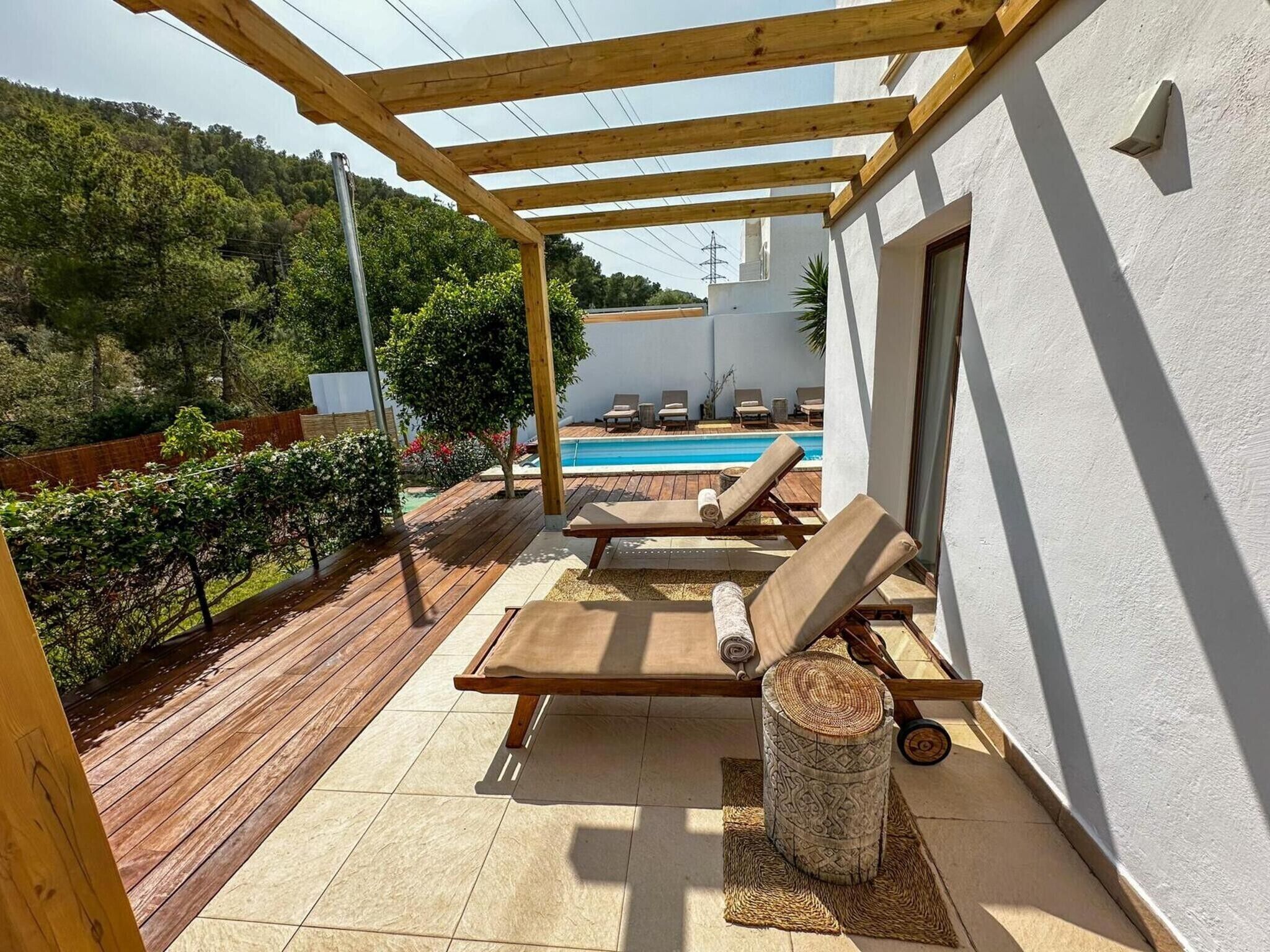 Een overdekt buitengebied met een zwembad, ligbedden en een pergola.