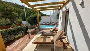 Ein überdachter Außenbereich mit Pool, Liegestühlen und einer Pergola.