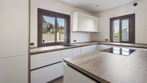 Eine moderne Küche mit weißen Schränken, einer Holzauskładung und einem Fenster mit Blick auf Grünflächen.