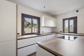 A modern kitchen with white cabinetry, a wooden countertop, and a window with a view of greenery. - Villa 'Dorada' with Sea Views, Wi-Fi and Air Conditioning (Unknown)