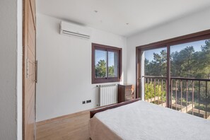A bedroom with a bed, a radiator, an air conditioning unit, a window, and a balcony with a view of trees. - Villa 'Dorada' with Sea Views, Wi-Fi and Air Conditioning (Unknown)