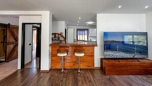 Eine moderne Küche mit einer Holztresore, zwei Barhocker und einem großen Fernseher auf einem Holzständer.