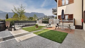 En boligejendom med terrasse, grill, stenvæg og udsigt til bjerge.