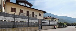 Un edificio con balcón, entrada protegida por una reja y una montaña al fondo.