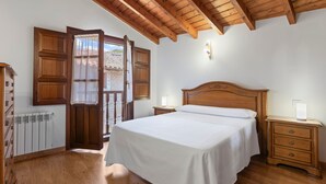 A bedroom with a wooden ceiling, a bed with white bedding, a nightstand with a lamp, and a wooden wardrobe. - Apartment 'La Mata' with Balcony and Wi-Fi (Bustio)