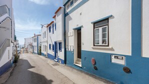A narrow street lined with buildings painted in white and blue, featuring doors and windows.