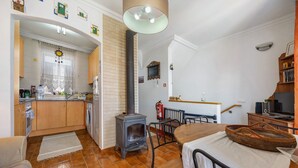 A kitchen with a wood-burning stove, a dining area with a table and chairs, and a view of the living room.