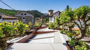 Un quartier résidentiel caractérisé par une architecture traditionnelle, des jardins en terrasses et un paysage de collines en arrière-plan.