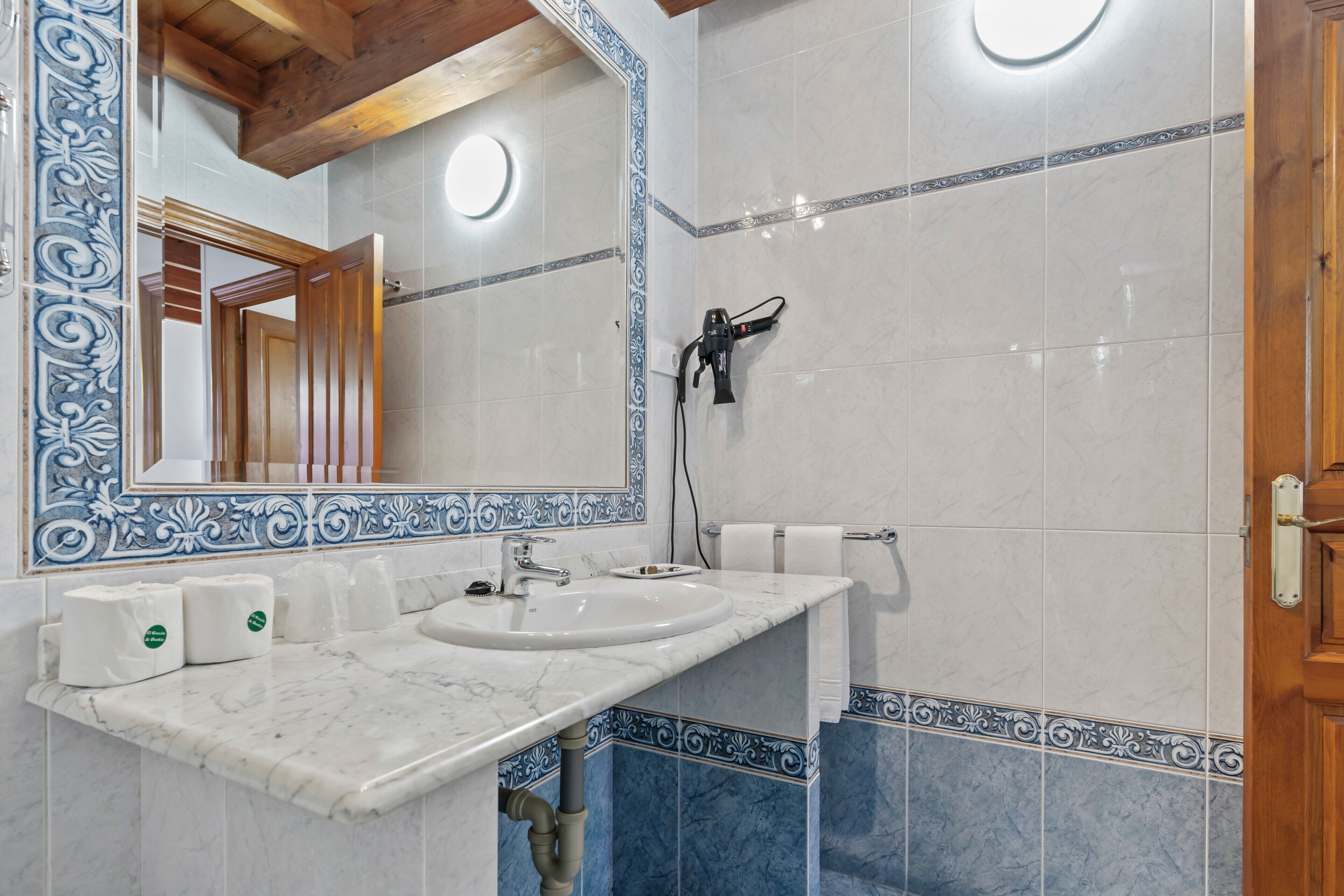 A bathroom with a marble sink, a towel rack, and a mirror with a decorative border.