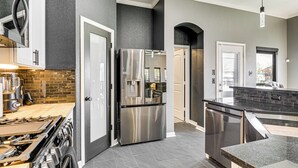 Une cuisine moderne avec des appareils en acier inoxydable, un mur recouvert de briques et un mur de couleur gris foncé.