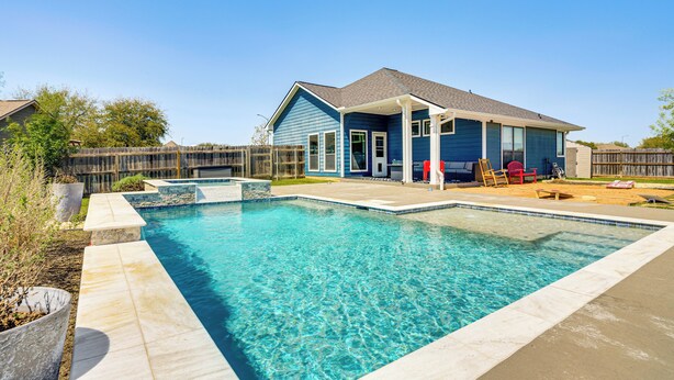Une piscine rectangulaire à l’eau d’un bleu limpide, entourée d’une terrasse en béton.