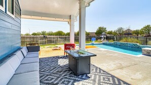 Un patio couvert avec une piscine, des sièges d’extérieur et un réfrigérateur pour boissons.