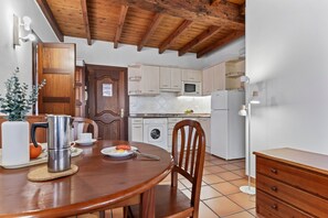 Una cucina con mobili in legno, un forno a microonde, un frigorifero, un lavello e un tavolo da pranzo con sedie.