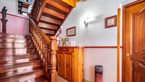 A wooden staircase with a handrail, a wooden reception desk, a door, and a wall-mounted light fixture. - Apartment 'Cantu' with Private Terrace, Balcony and Wi-Fi (Bustio)