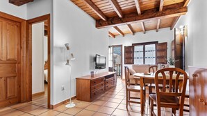 A room with a wooden ceiling, tiled floor, a dining table with chairs, a TV, and a wooden cabinet. - Apartment 'Cantu' with Private Terrace, Balcony and Wi-Fi (Bustio)