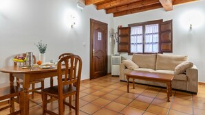 Une pièce comprenant une table à manger en bois, des chaises, un canapé, une table basse, une fenêtre avec des rideaux et une porte.