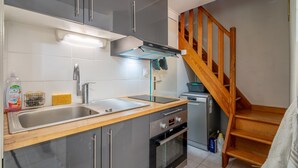 A kitchen with a stainless steel sink, a built-in oven, and a wooden staircase. - Holiday Home 'Hameau Du Soleil' with Shared Pool, Private Terrace and Private Garden (Vendres)