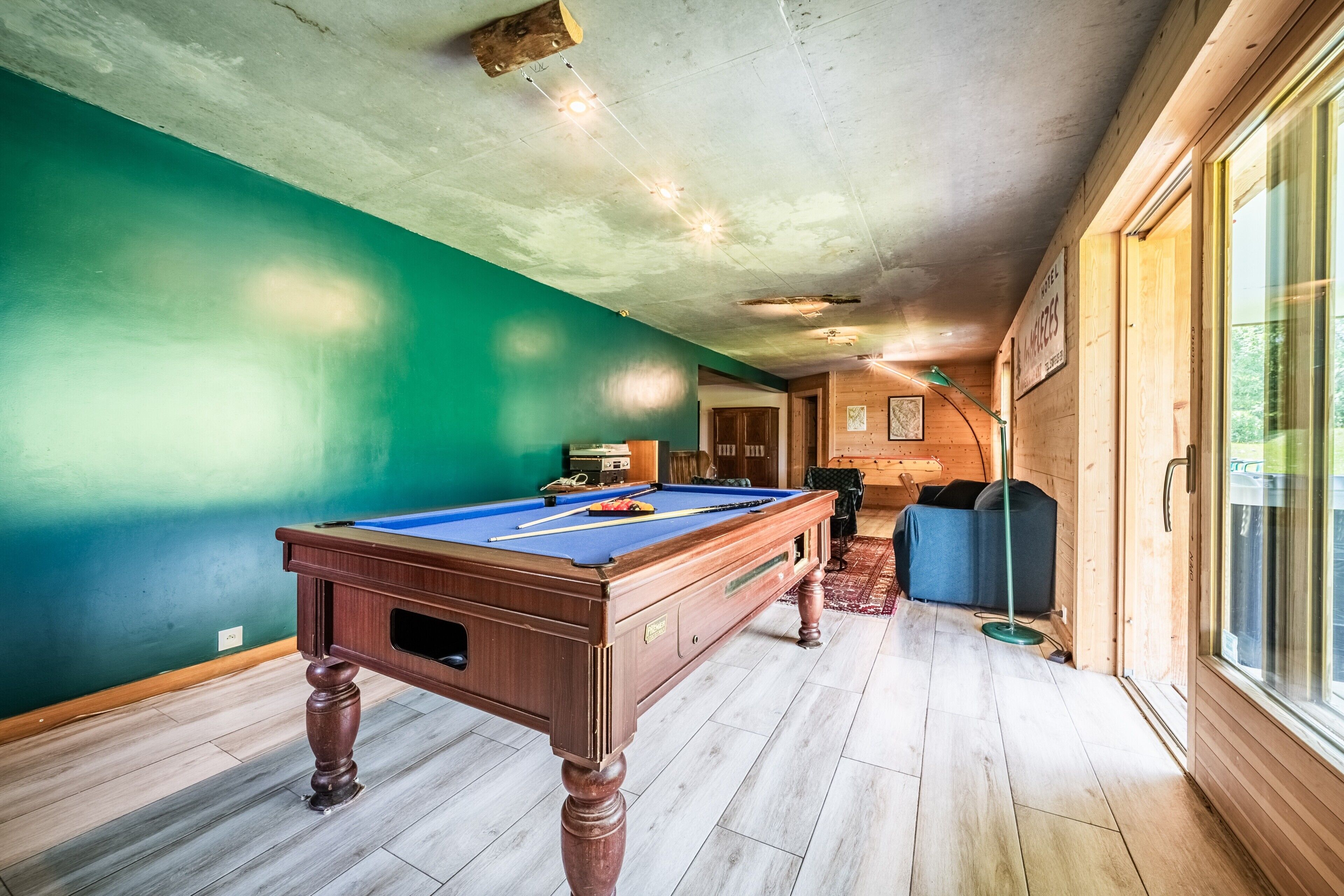 Een pooltafel in een ruimte met houten vloeren en een groene wand.