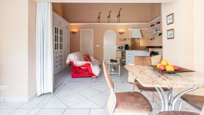 A compact living space with a dining area, kitchenette, and a cozy seating area with a red sofa. - Apartment 'Finca 9' with Shared Pool, Wi-Fi and Air Conditioning (Moraira)