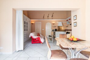 Un espacio habitable compacto con comedor, kitchenette y una zona de estar acogedora con sofá rojo.