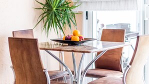 A dining table with a fruit bowl, four chairs, a potted plant, and a window with blinds. - Apartment 'Finca 9' with Shared Pool, Wi-Fi and Air Conditioning (Moraira)