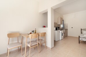 A modern kitchen with a washing machine, a dining area with a table and chairs, and a bed in the corner. - Apartment 'Panagis 2' with Mountain View, Wi-Fi and Air Conditioning (argostoliou)