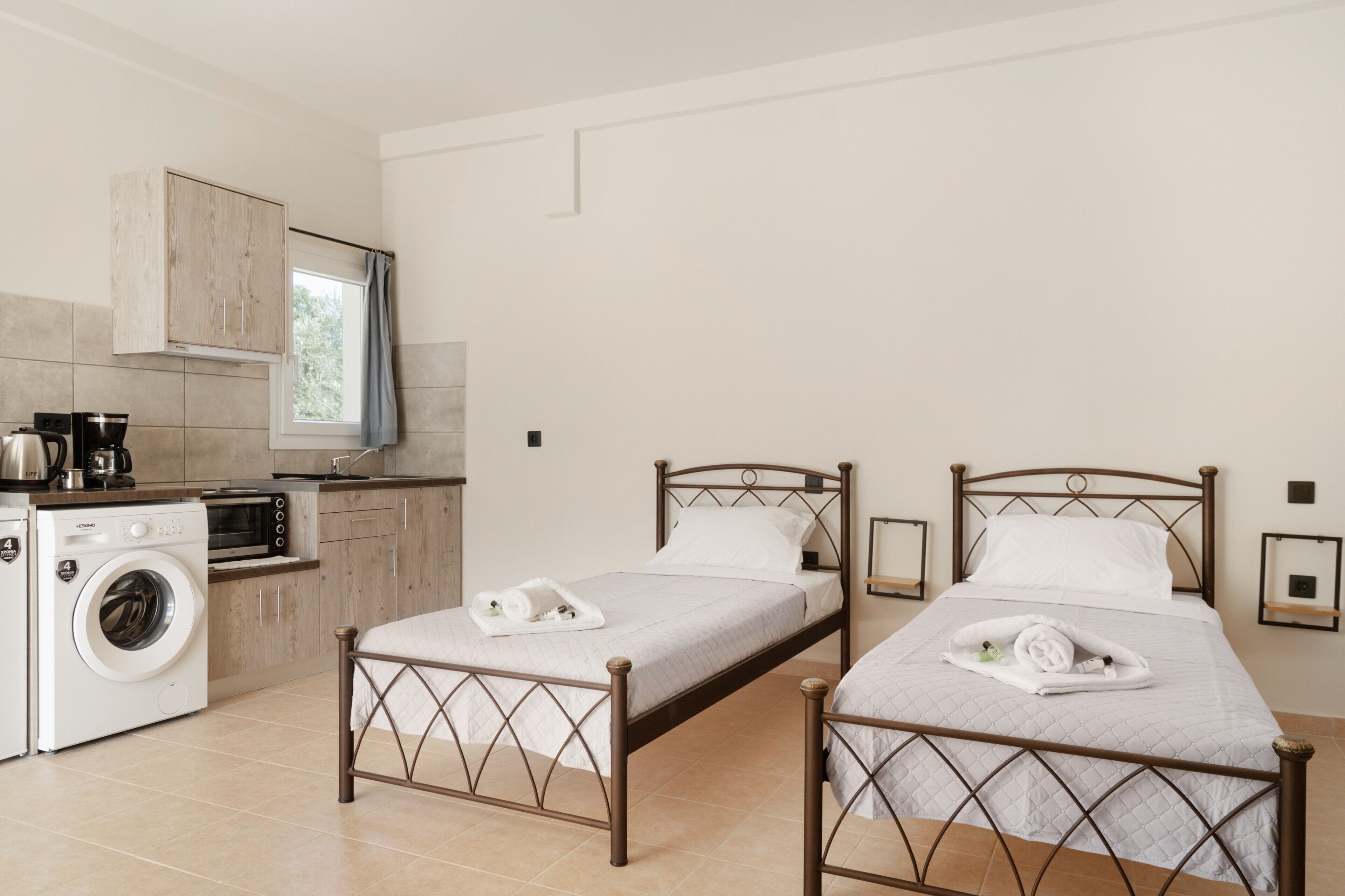 A compact room with two beds, a washing machine, and a kitchenette.