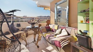 A balcony with a sofa, a table, and a decorative mirror.