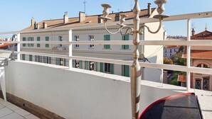 A balcony with a white railing, a metal lamp post, and a view of a building with green shutters. - Apartment 'Le Loft' with Mountain View, Wi-Fi and Air Conditioning (Cannes)