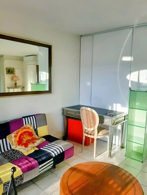Un salon moderne comprenant un canapé, une table à manger, une chaise, une petite table basse ronde et un grand miroir.