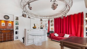 A modern living space with a kitchen, dining area, and a red curtain.