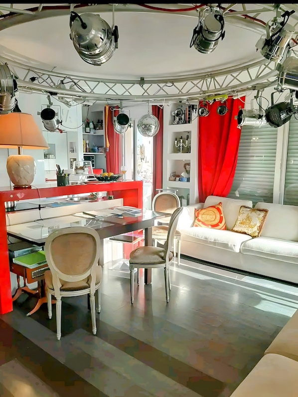 Un intérieur moderne avec un coin repas, un canapé et une cuisine en arrière-plan.