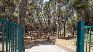 A wooden pathway leading through a forested area with a metal gate on the left. - Vacation Home 'Karma' with Sea View and Air Conditioning (Gallipoli)