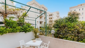 A balcony with a white table and chairs, surrounded by greenery and a metal trellis. - Vacation Home 'Karma' with Sea View and Air Conditioning (Gallipoli)