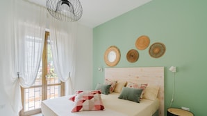 A bedroom with a bed, curtains, a wall-mounted mirror, and a round table. - Vacation Home 'Karma' with Sea View and Air Conditioning (Gallipoli)