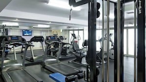 Une salle de sport équipée de tapis de course, de vélos d’appartement et d’appareils de musculation.