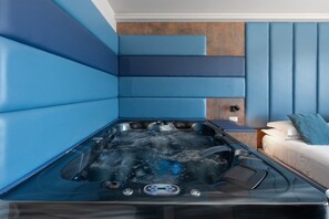 Et moderne spa-rum med et boblebad, en seng og et vægmonteret massagebord.