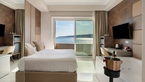 Une chambre d’hôtel avec un lit, un bureau, une télévision et une vue sur la mer.