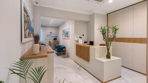 Un espace d’accueil avec un comptoir en bois, une chaise bleue et une plante.