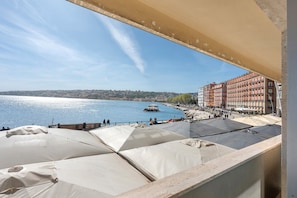 Une terrasse agrémentée de parasols, donnant sur le bord de l’eau, avec des bâtiments en arrière-plan.