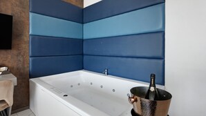 Ein modernes Badezimmer mit einer großen Badewanne, einem an der Wand montierten Fernseher und einer Champagnerflasche in einem Kupferkübel.