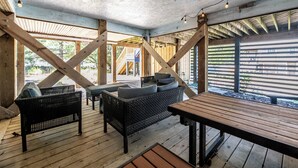 An outdoor patio with wicker furniture, a wooden table, and string lights. - Lucky Fin - Corolla, Ocean Sands, Oceanside, 600 Yds to Beach, 4 Bedrooms, Hot Tub, Pets OK! (Corolla)