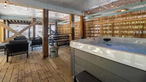 A wooden deck area with a hot tub, outdoor seating, and a bamboo wall. - Lucky Fin - Corolla, Ocean Sands, Oceanside, 600 Yds to Beach, 4 Bedrooms, Hot Tub, Pets OK! (Corolla)