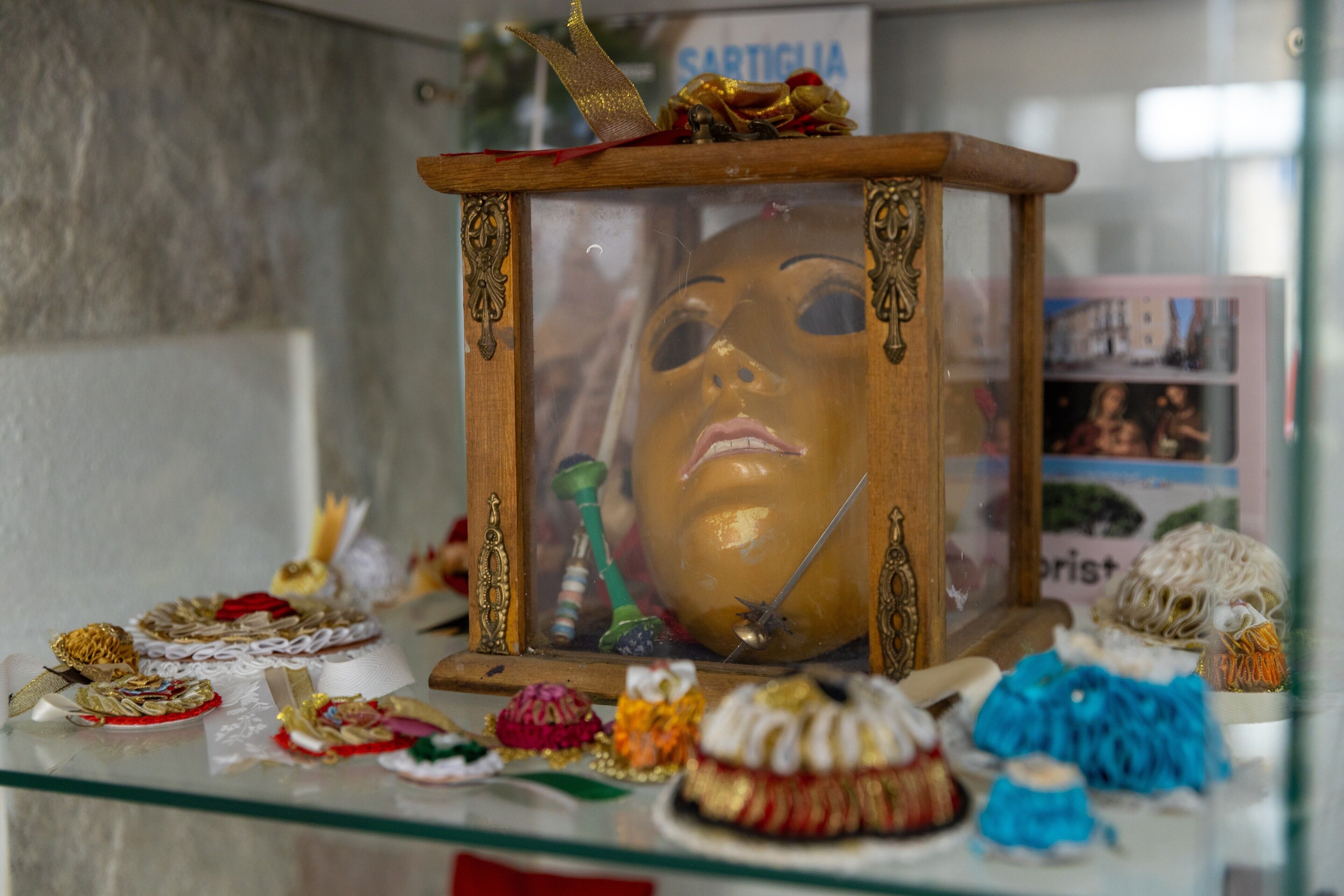 Eine Vitrine mit Holzrahmen, die eine Maske und verschiedene Dekorationsgegenstände beherbergt.