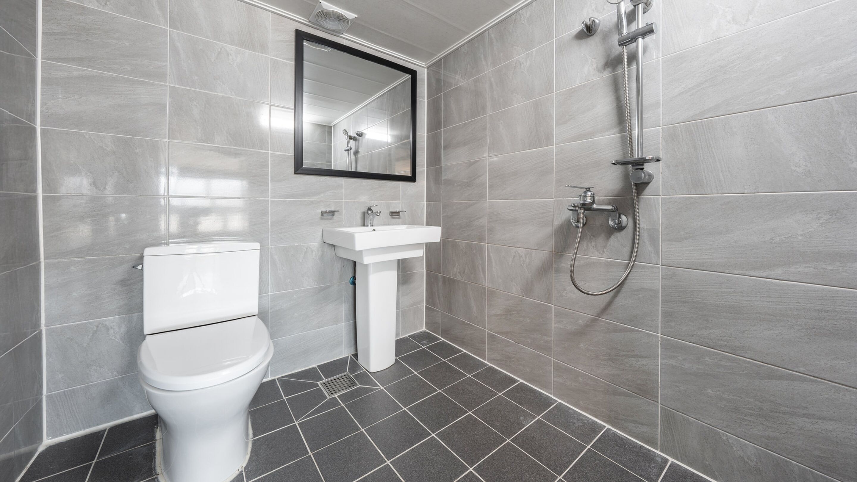 A modern bathroom with a toilet, sink, and shower.