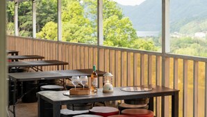 Un espace de restauration en plein air avec des tables, des chaises, une bouteille de boisson alcoolisée et une lanterne.
