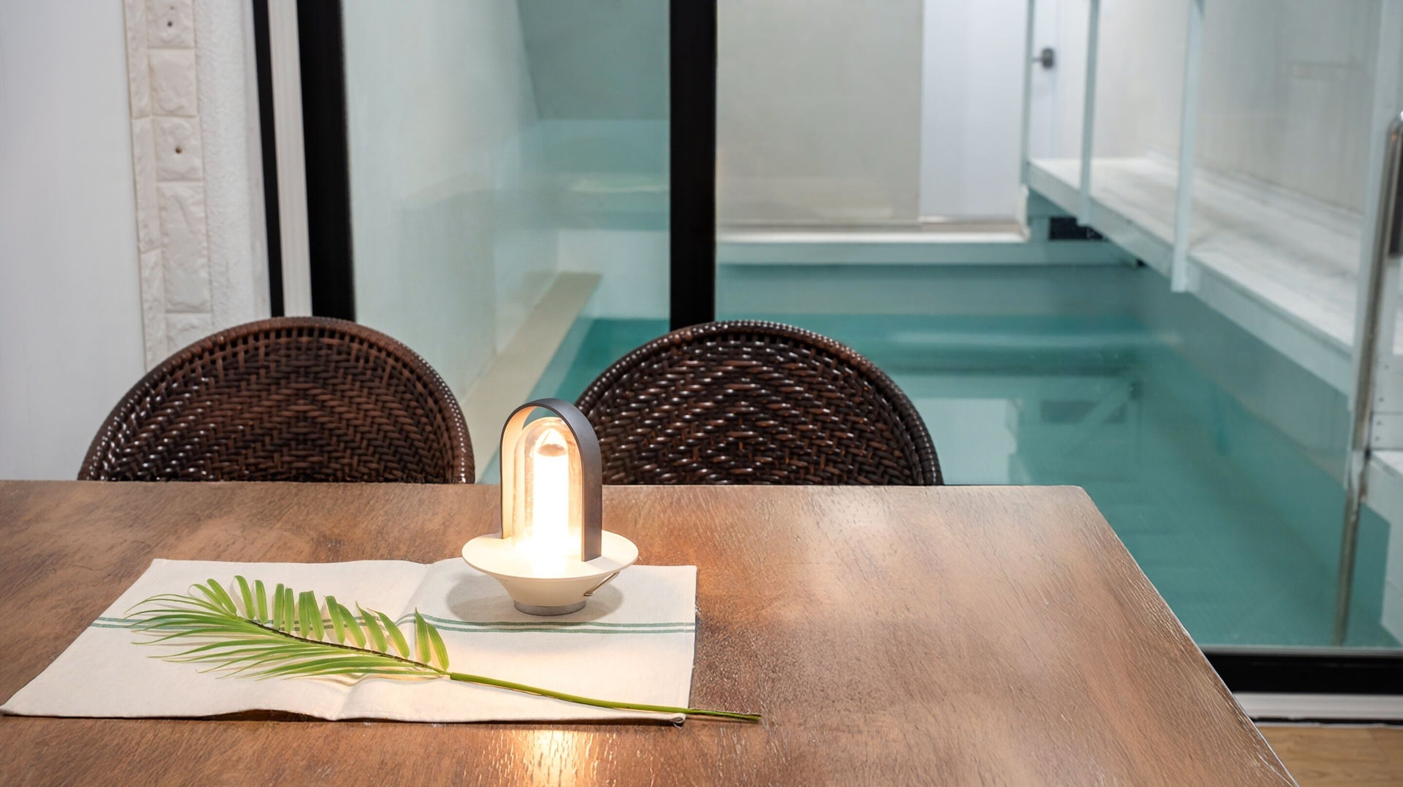 A dining table with a candle, a placemat, and a palm leaf.