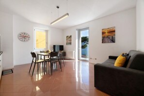 A spacious living area with a dining table, sofa, and artwork on the walls.